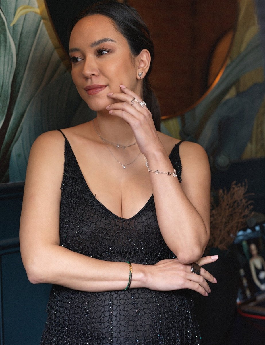 Woman wearing a black dress showcasing a wood malachite bracelet with silver spacer beads.