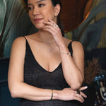 Woman wearing a black dress showcasing a wood malachite bracelet with silver spacer beads.